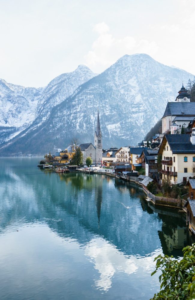 A beautiful shot of a small village surrounded by a lake and snowy hills