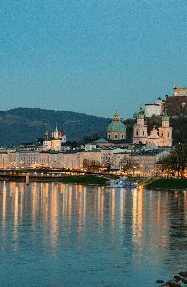 Dusk view down the river with reflections of street lights and a castle in the background