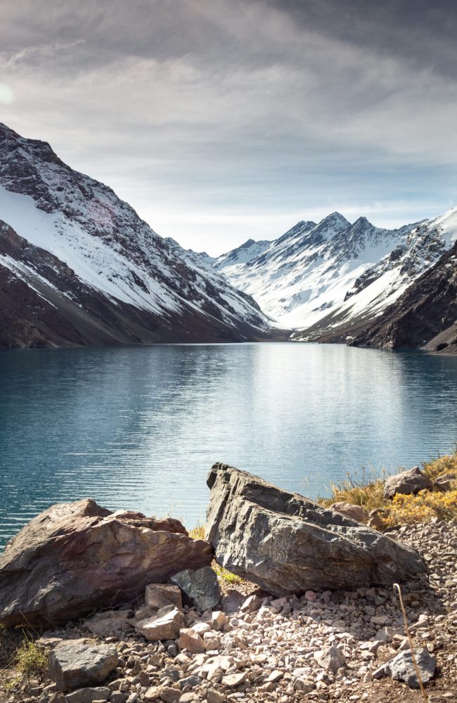The Laguna del Inca lake surrounded by high mountains covered in snow in Chile
