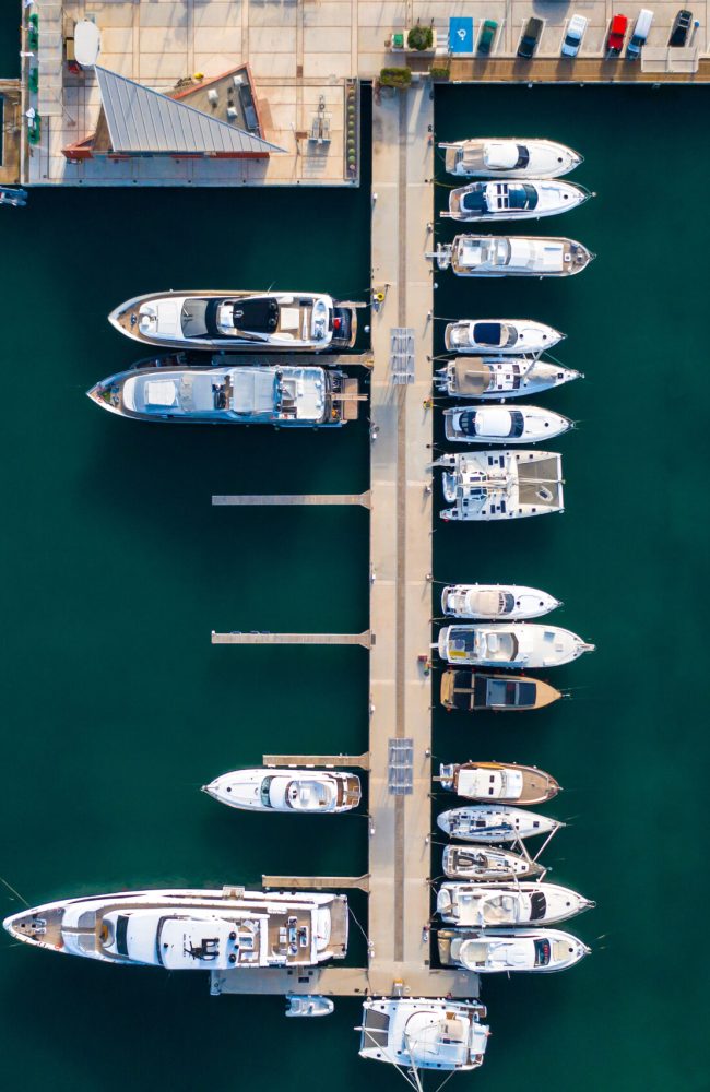 Landscape with boats in marina bay, sea, buildings in city. Top view of harbor with sailboat.