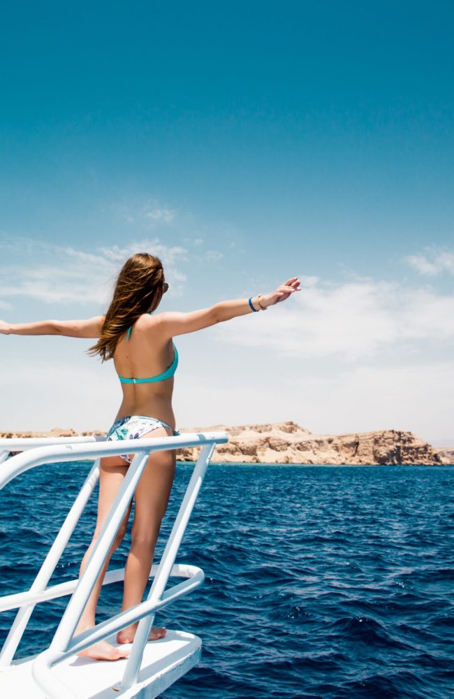 Woman standing on the nose of the yacht at a sunny summer day